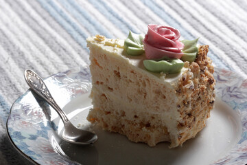 Piece of sweet meringue cake with cream rose
