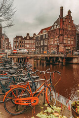 Many Bikes parked by canal in rainy day. Picturesque town landscape in Netherlands.