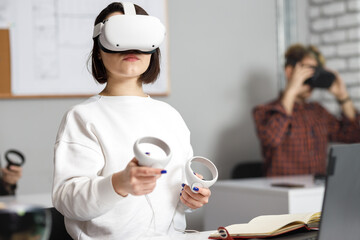 team of four creative engineers working with virtual reality, young woman testing VR glasses or...