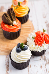 Cupcakes or muffins with white cream and berries. Cake celebration, delicious dessert, close-up