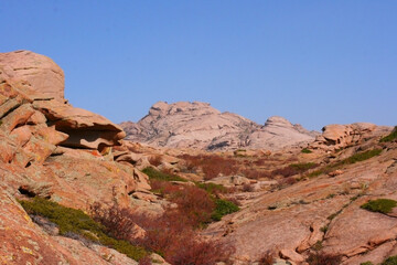 View of a Rock at Katutau red mountain range on a sunny blue sky day. Nature reserve Altyn Emel. Kazakhstan. Rock formations with interesting shapes. Frozen lava stones.