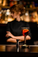 glass of alcoholic cocktail and jigger stands on bar