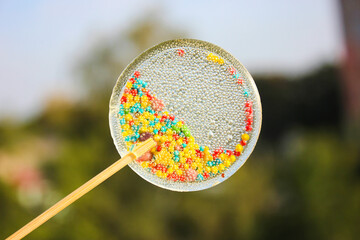 Transparent candy on a stick. Lollipop with colored sprinkles inside. Close-up view.