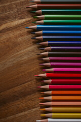 Colored pencils with selective focus on wooden background. 