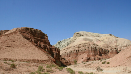 Fototapeta premium Aktau Mountains on sunrise. Beautiful landscape of colorful mountains in desert. Nature reserve Altyn Emel. Kazakhstan. Panorama with copy space