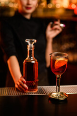 Close-up view of glass with cold cocktail and bottle with drink on bar