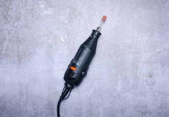 Electric mini drill on concrete background, top view space for text