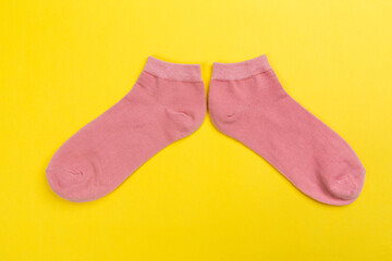 Top view of a pair of colored socks on a yellow background. Clothing in the form of socks.