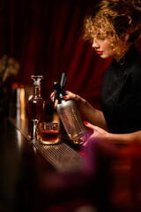 view of bar counter with bar equipment behind which female bartender prepares cocktail