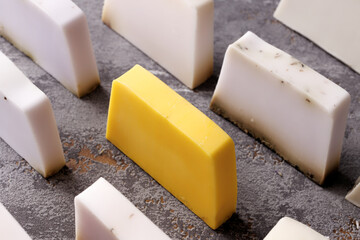 Assortment of soap bars in rows with yellow bar in the centre from top view. Natural herbal colorful soaps.