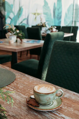 Coffee in blue cup on wooden table in cafe with lighting background. Place for text.