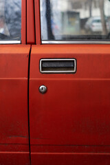Vintage chrome door handle on red car rough aged surface on a Russian or Eastern European classic car in Sofia, Bulgaria