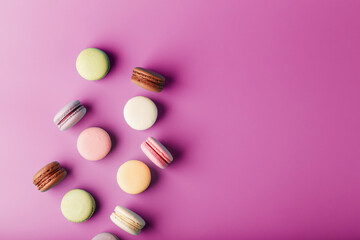 Colorful French macaroni cookies are scattered on a pink background.