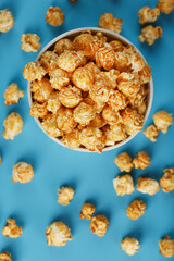 Caramel of the popcon in a white cup with a scissor on a blue background.