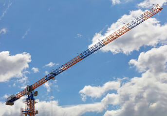 An arrow of a tower crane against a blue sky, divides the image diagonally.