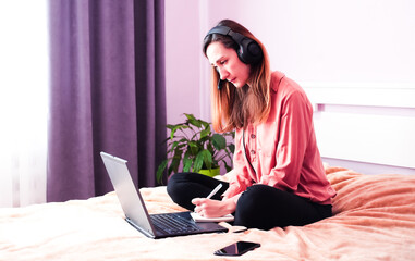 Focused woman in headset listening audio course or watching online webinar at home. E-learning...