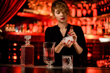 crystal decanter, mixing cup and glass stand on bar counter and woman bartender crash ice