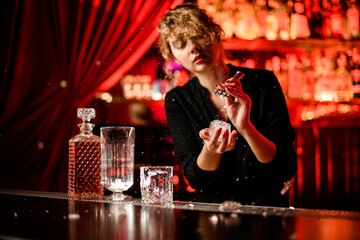 woman at bar breaks large piece of ice with pick and small pieces fly around