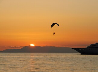 A powered paraglider, flying at sunset, in Glyfada, Greece