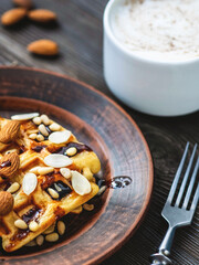 Viennese waffles with chocolate and nuts and a cup of cappuccino