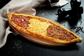 Turkish pide dish with three different fillings: lamb, beef and cheddar cheese on a black...