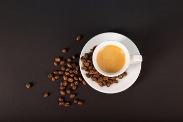 A cup of espresso coffee, a bunch of roasted coffee beans on a dark background. View from above.