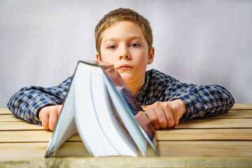 Education concept. The boy puts a book on a wooden table.