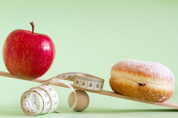 Apple and donut with a tape measure on wooden seesaw, healthy lifestyle concept