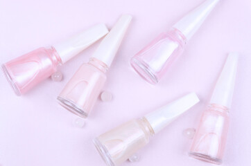 Bottles of pink pastel nail polish on a pink background.