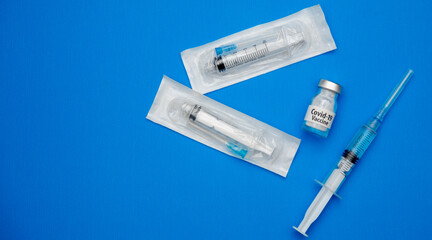 Obraz premium Coronavirus vaccine concept and syringe on blue background with copy space