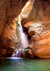 waterfall passing between rocks with light streaming overhead