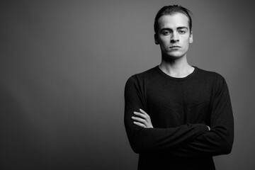 Young handsome man wearing long sleeved shirt against gray background
