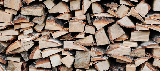 Chopped birch firewood stacked in a woodpile. Raw materials, fuel for heating houses and wood-fired boilers. Front view. Firewood background image