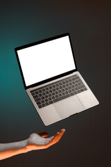 Levitating laptop with keyboard, blank copy space and male hand isolated on green background, for...