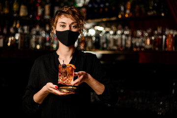view of woman in black mask and holding glass with cocktail