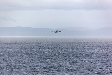 The rescue helicopter saves the fishermen who fell from the boat to the stormy Barents sea, Northern Norway.