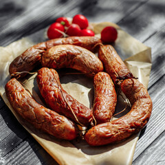 Smoked sausage on a wooden rustic table with addition of fresh aromatic herbs and spices, natural product from organic farm, produced by traditional methods