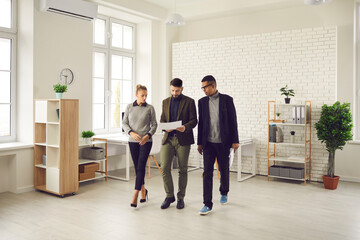 Office workers on the go review documents and discuss new business development strategies and...