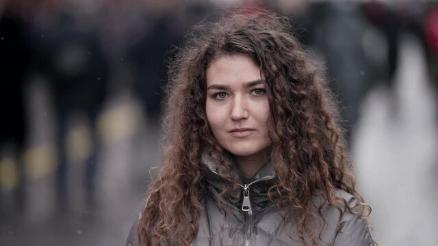 positive young woman in city, portrait on street against grey silhouettes of people, crowd in background