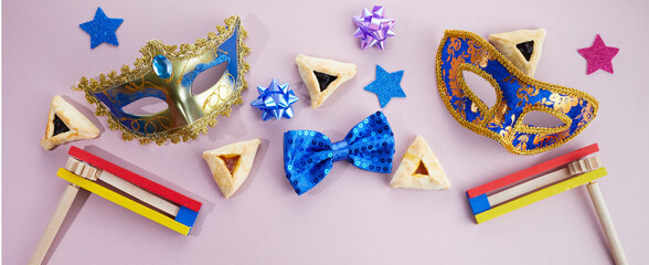 Purim celebration. Hamantashen or haman ears, noisemaker and mask on grey background. Top view