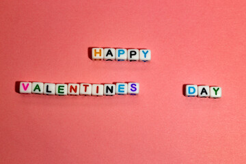 the text of "happy valentine's day" made of cubes, on a pink background