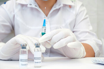 COVID-19 vaccine in researcher hands, female doctor holds syringe and bottle with vaccine for coronavirus cure. Concept of corona virus treatment, injection