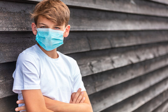 Boy teenager teen male child wearing face mask outside in the Coronavirus COVID-19 pandemic