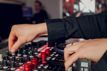 DJ's hand over the laptop and mixing console controlling the sound settings.