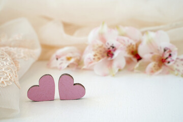 on a blurred delicate background with flowers two hearts next to each other. concept of tender love for valentines day