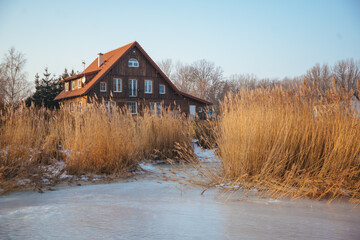 Idyllic house seen from frozen river in winter