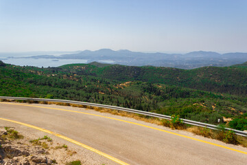 A winding road in the mountains of the island of Corfu in Greece with views of the Ionian Sea.