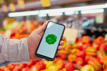 Natural product. A man holds a smartphone in his hands with a label on the screen against the...