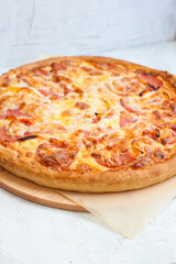Pizza with mozzarella cheese, ham, tomatoes and sauce on plain grey background