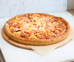 Pizza with mozzarella cheese, ham, tomatoes and sauce on plain grey background